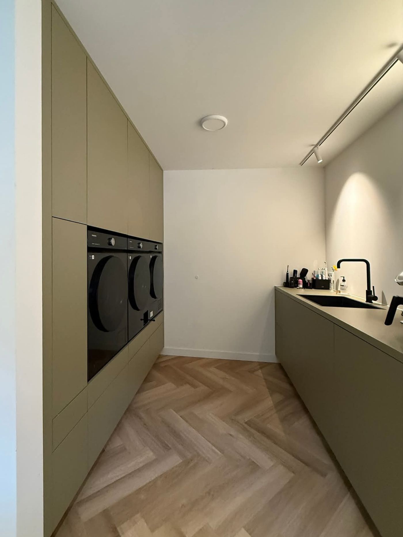 Groene bijkeuken met hoge kastenwand en werkblad