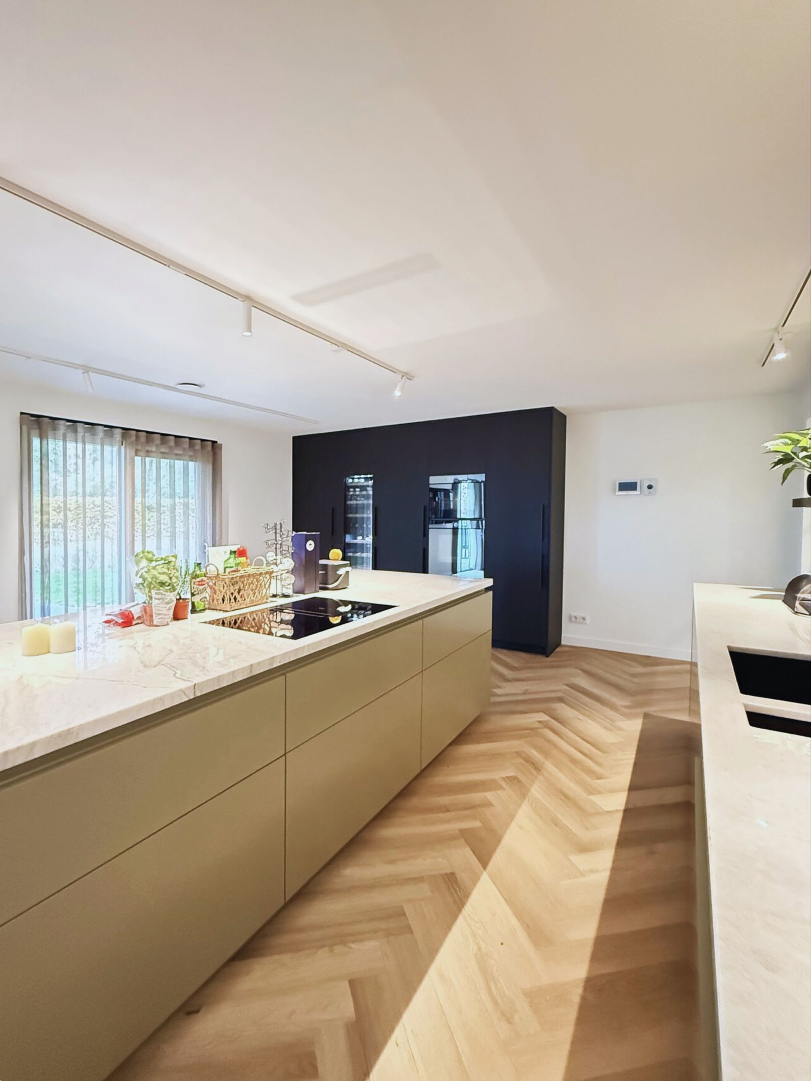 Keuken met kookeiland, natuursteen blad en zwarte apparatenwand